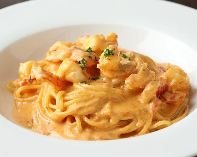 魚介を添えた手打ちパスタを白い皿に盛り付けた料理